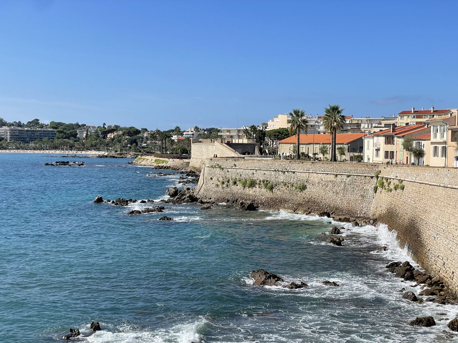 Antibes city walls meeting the turquoise Mediterranean, brilliant blue sky